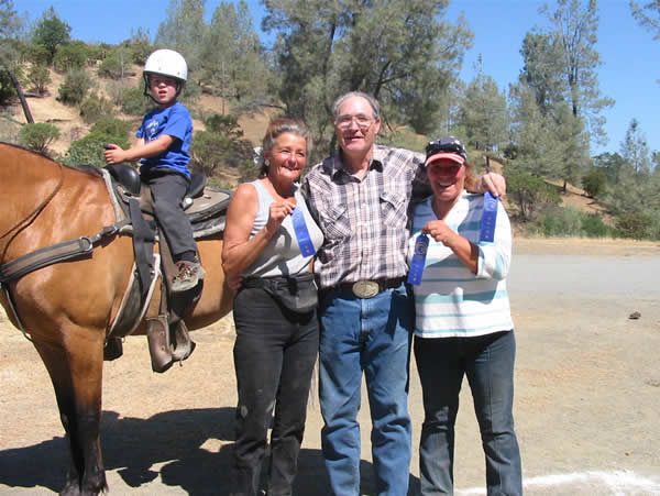 Friends and family with blue ribbons beside a horse at a Ranch gymkhana
